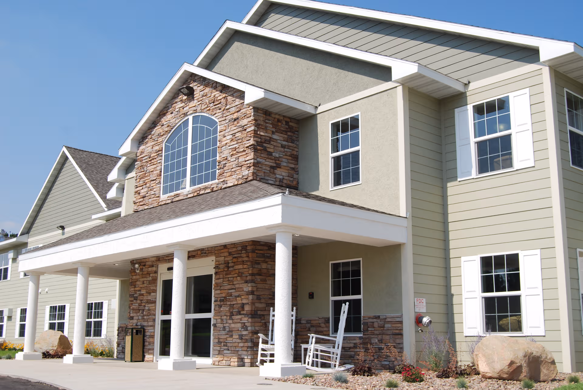 Exterior view of Woodstone Senior Living facility with stone facade and columns.