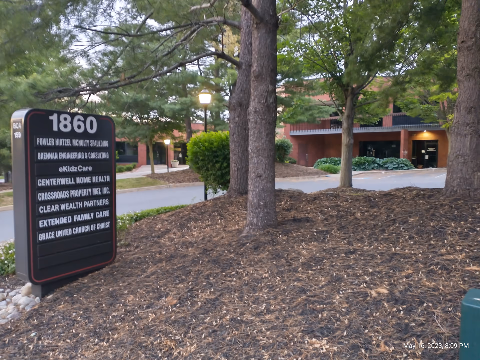 Outdoor scene with a large signboard, trees, and a building in the background.