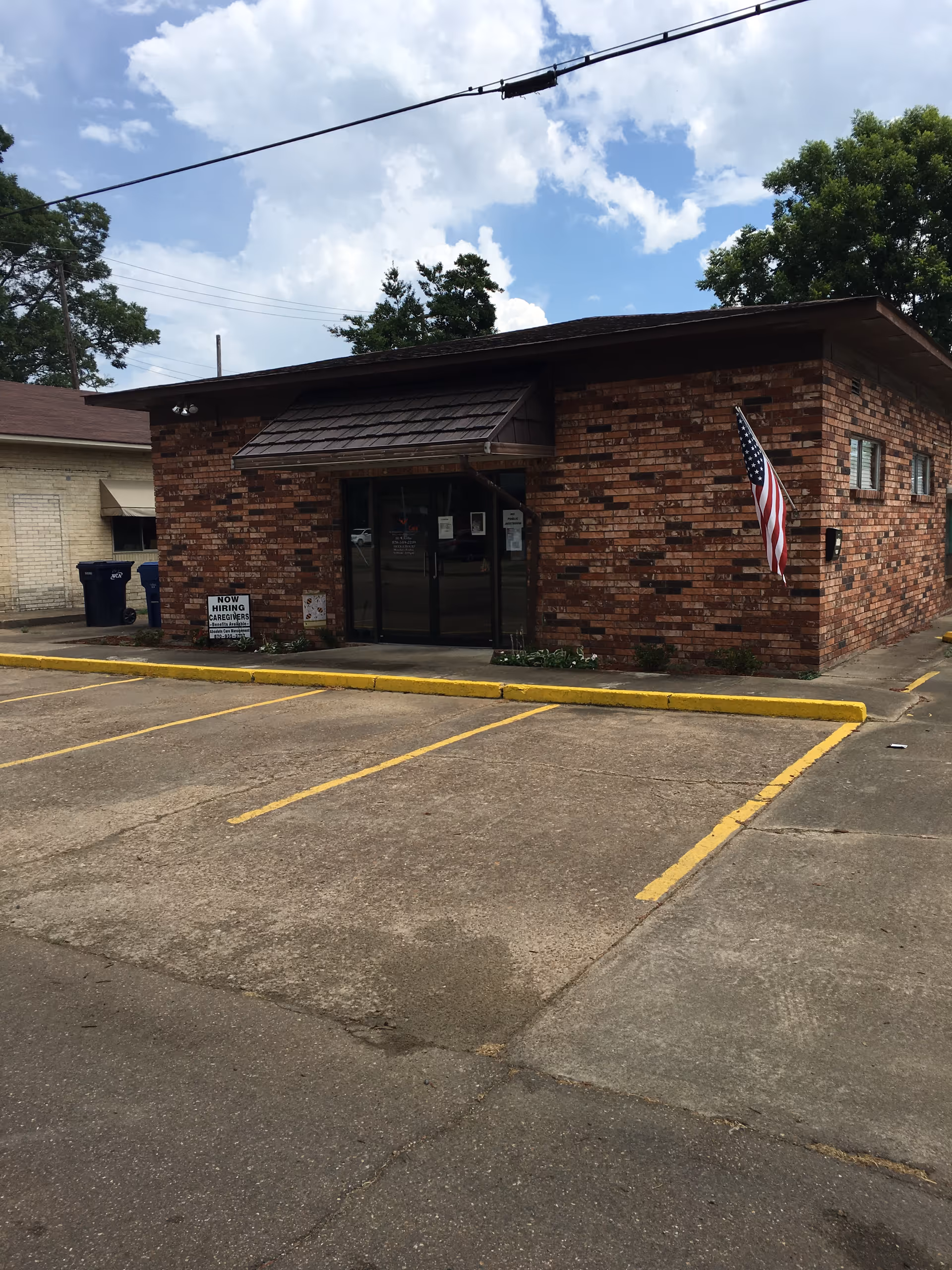 The brick facility entrance has glass doors, an American flag, and an empty parking lot.