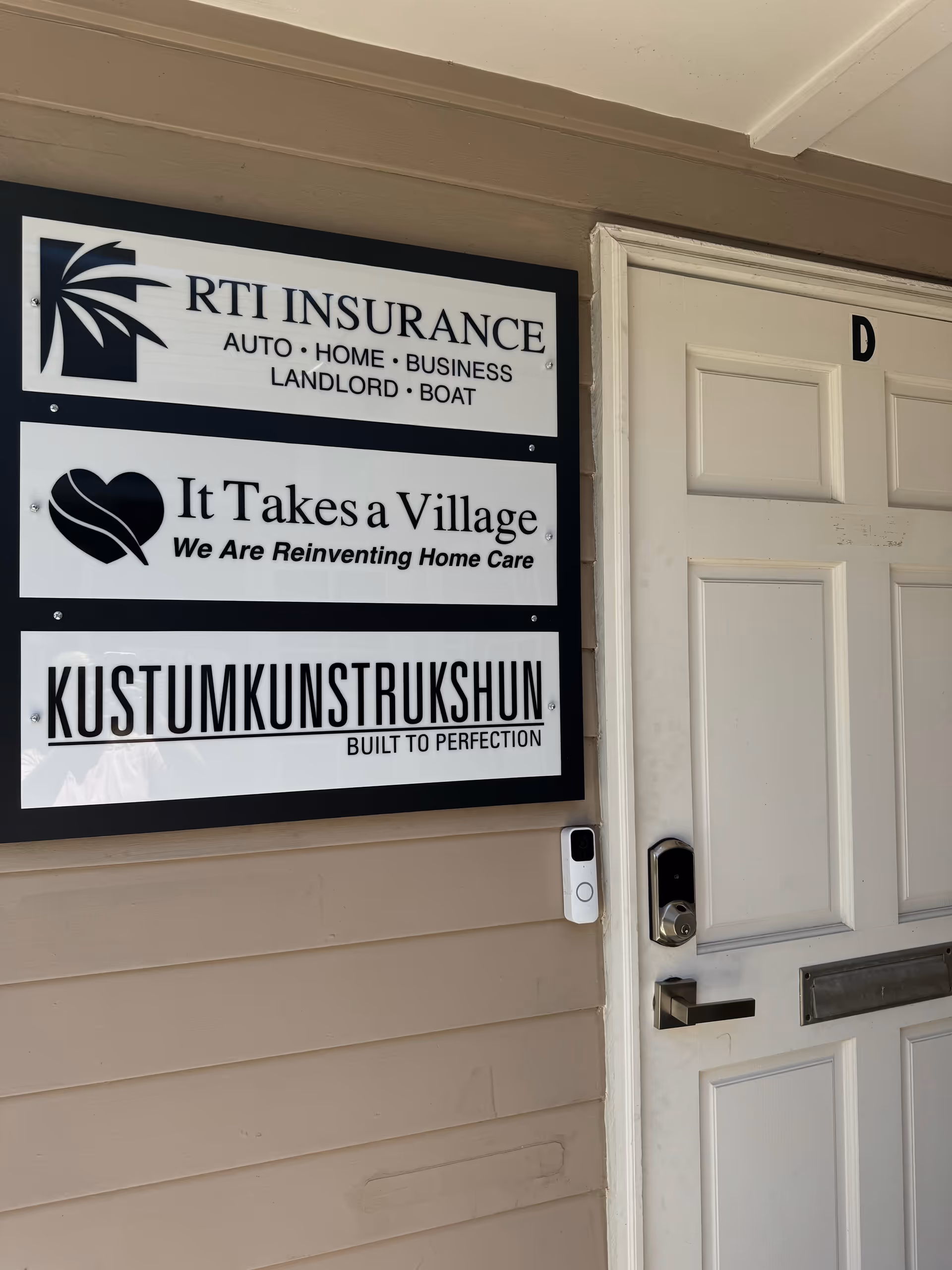 Exterior wall with It Takes a Village Senior Care sign beside a white door.