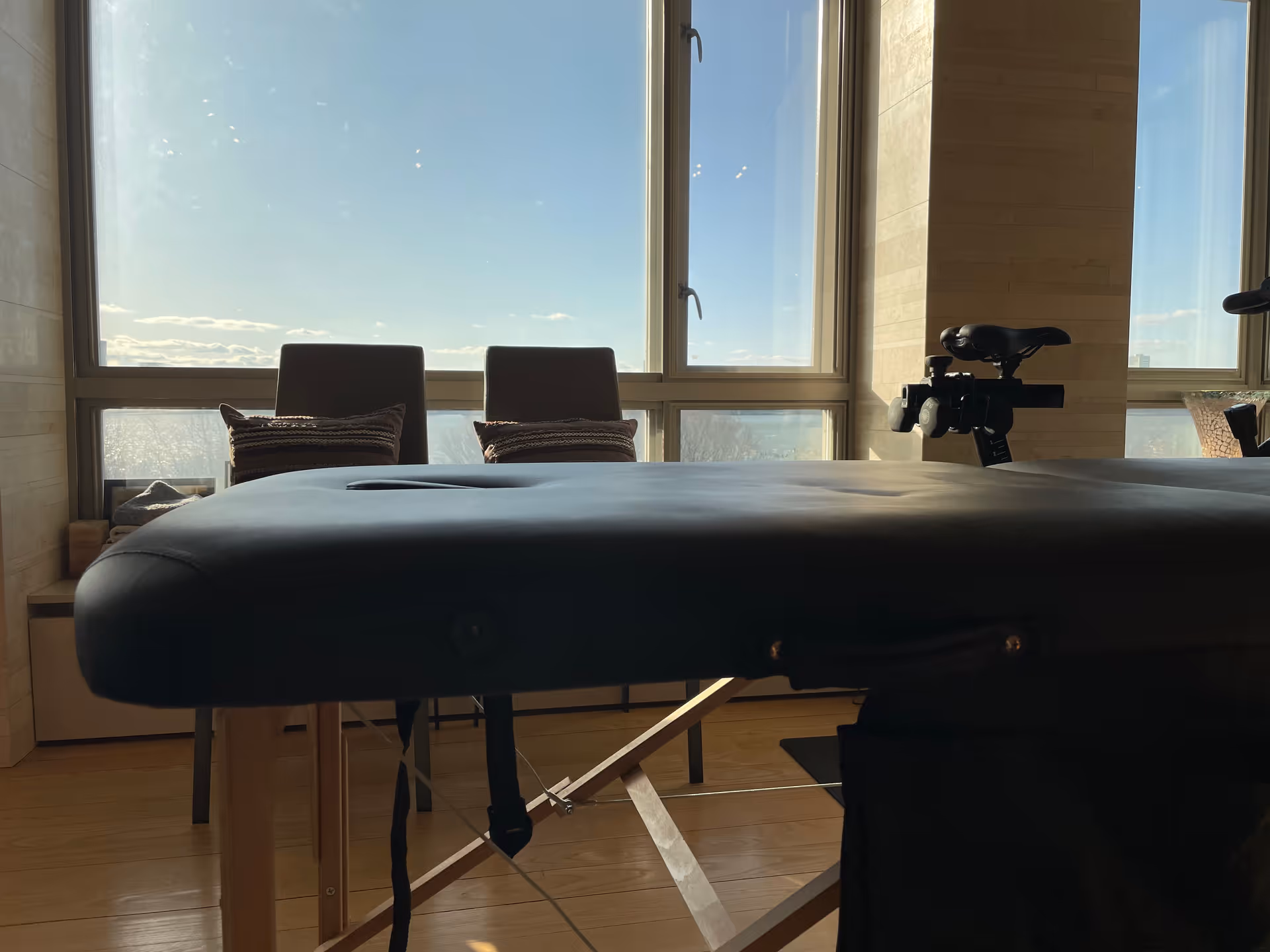 A padded therapy table in a bright interior room beside large windows.