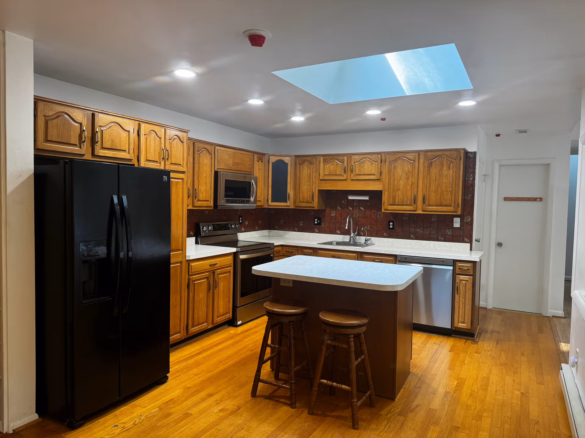 Bright kitchen in a senior living facility with wooden cabinets and an island.