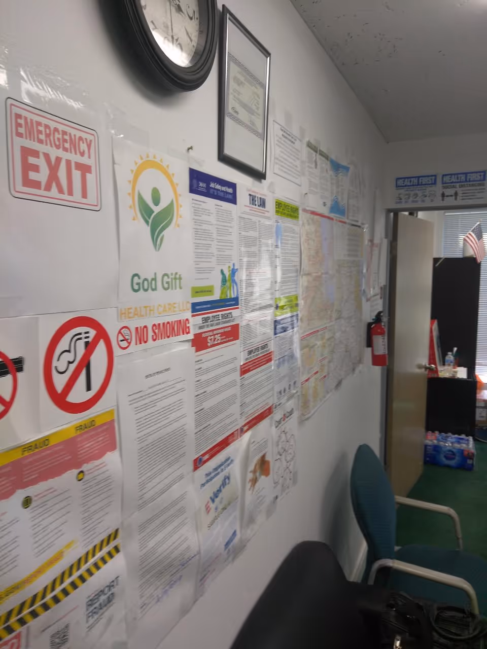 Indoor facility hallway with numerous posted notices and chairs along the wall.