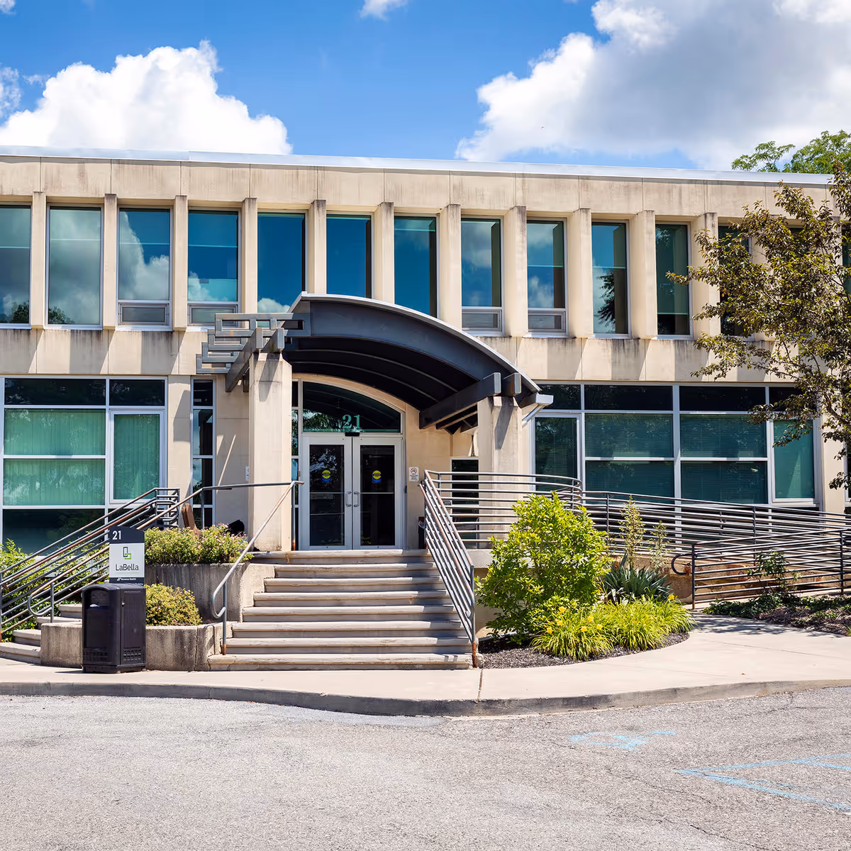 Front entrance of a modern medical building with glass windows and stairs.