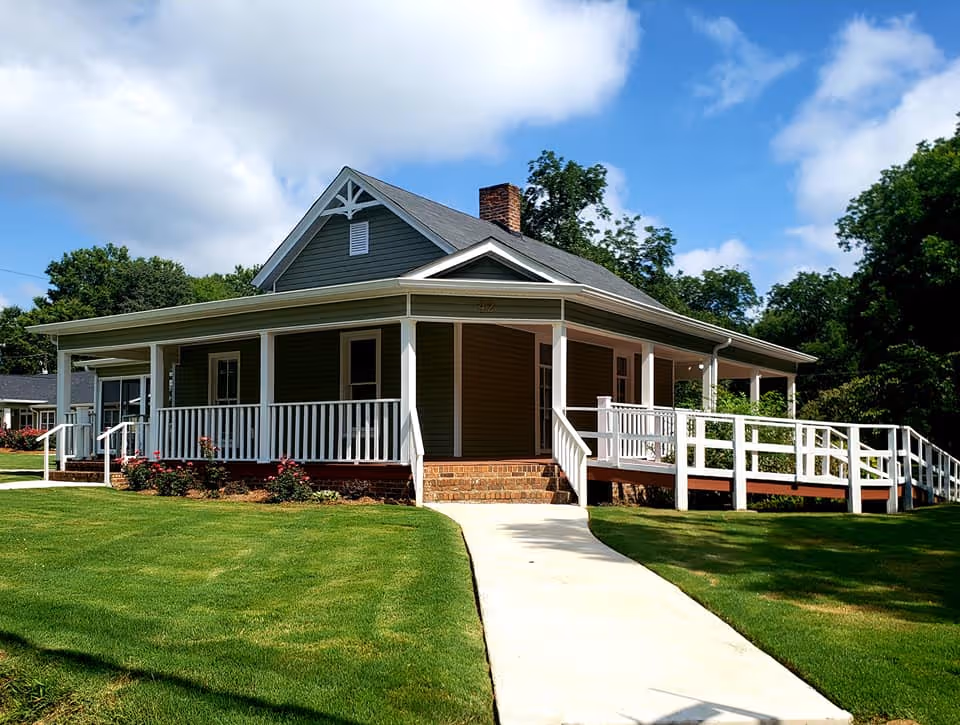 Single-story Craftsman-style senior living building with front porch and white railings.