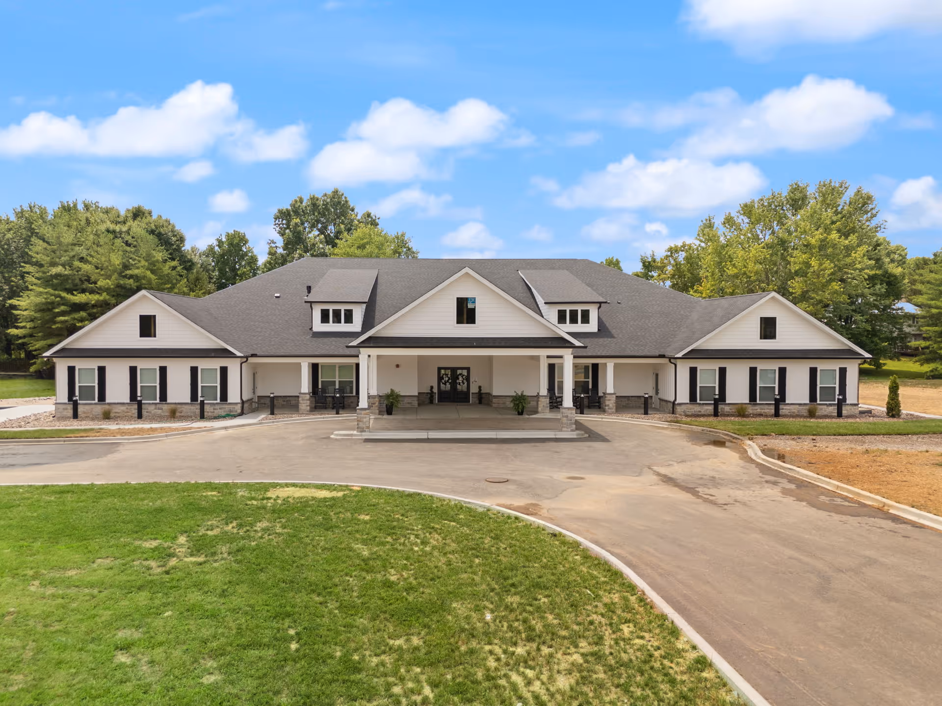 Exterior view of a single-story assisted living facility with a covered entrance and driveway.