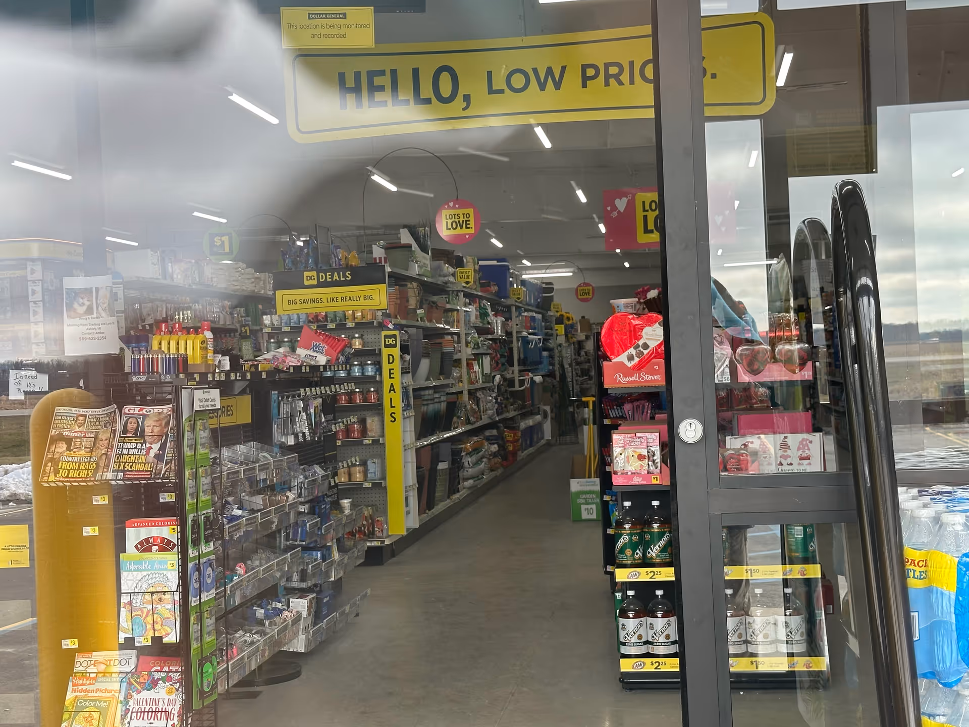 Through glass doors, a brightly lit convenience store interior with aisles and shelves.