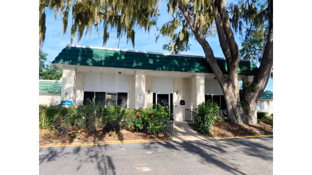 Front view of a senior living facility with green roof and trees.