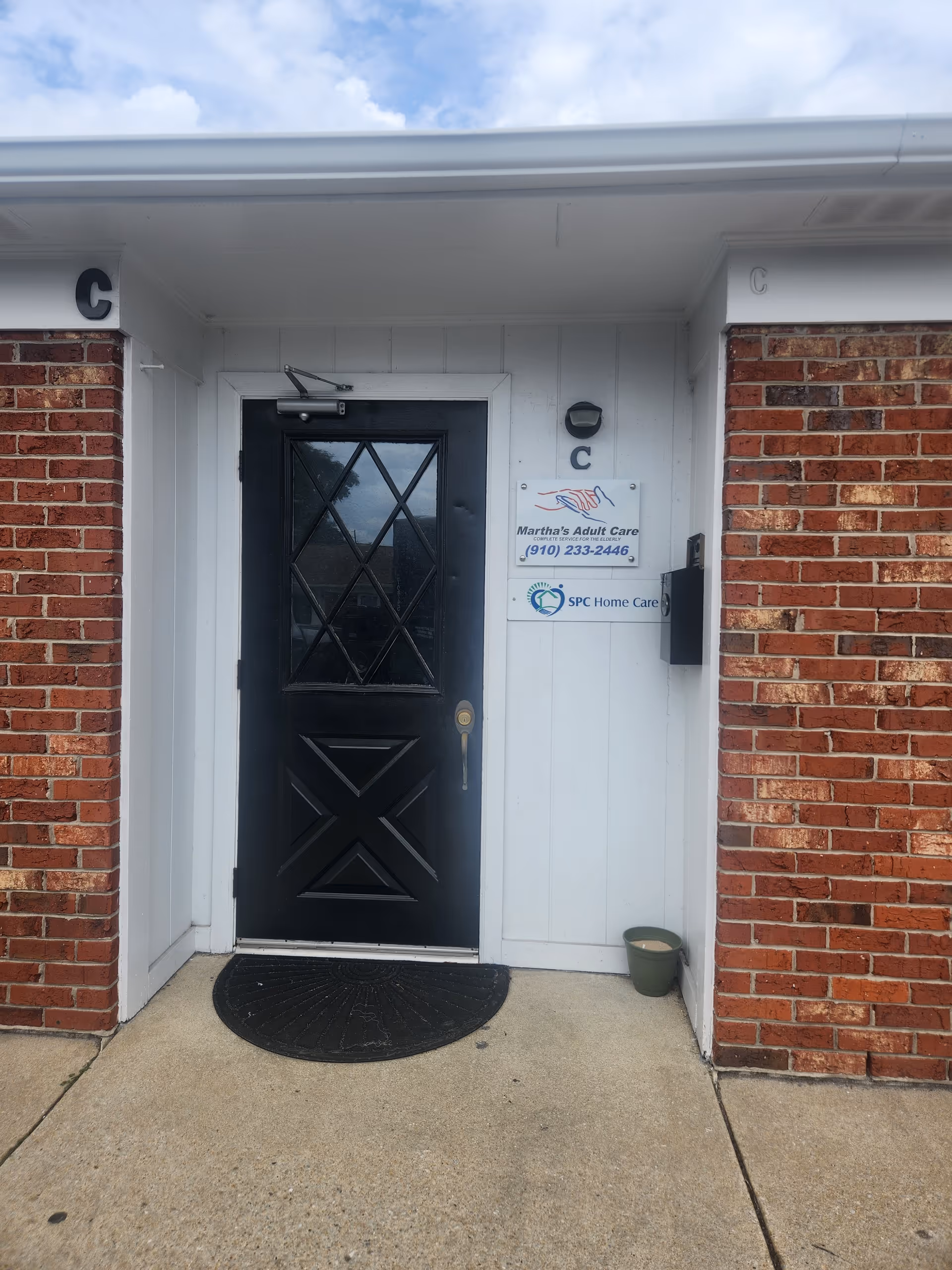 Brick exterior with a black front door and signboard beside the entrance.
