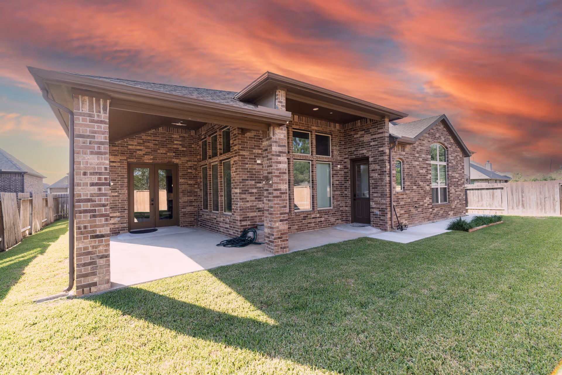 Brick, single-story senior living building with a covered patio and green lawn.