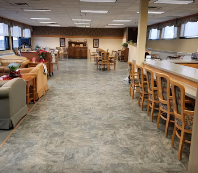 Interior common area of a senior living facility with couches, tables, and a bar-style counter.