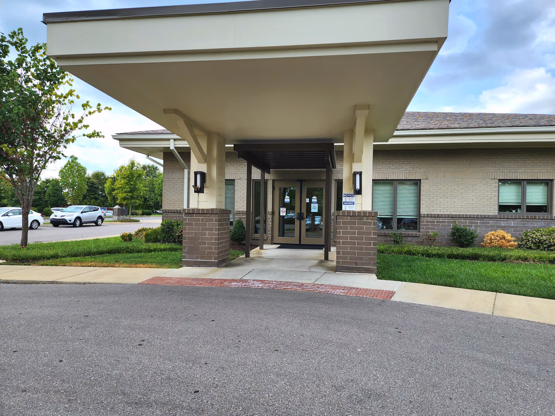 Exterior view of a brick facility entrance with a large covered drop-off area.