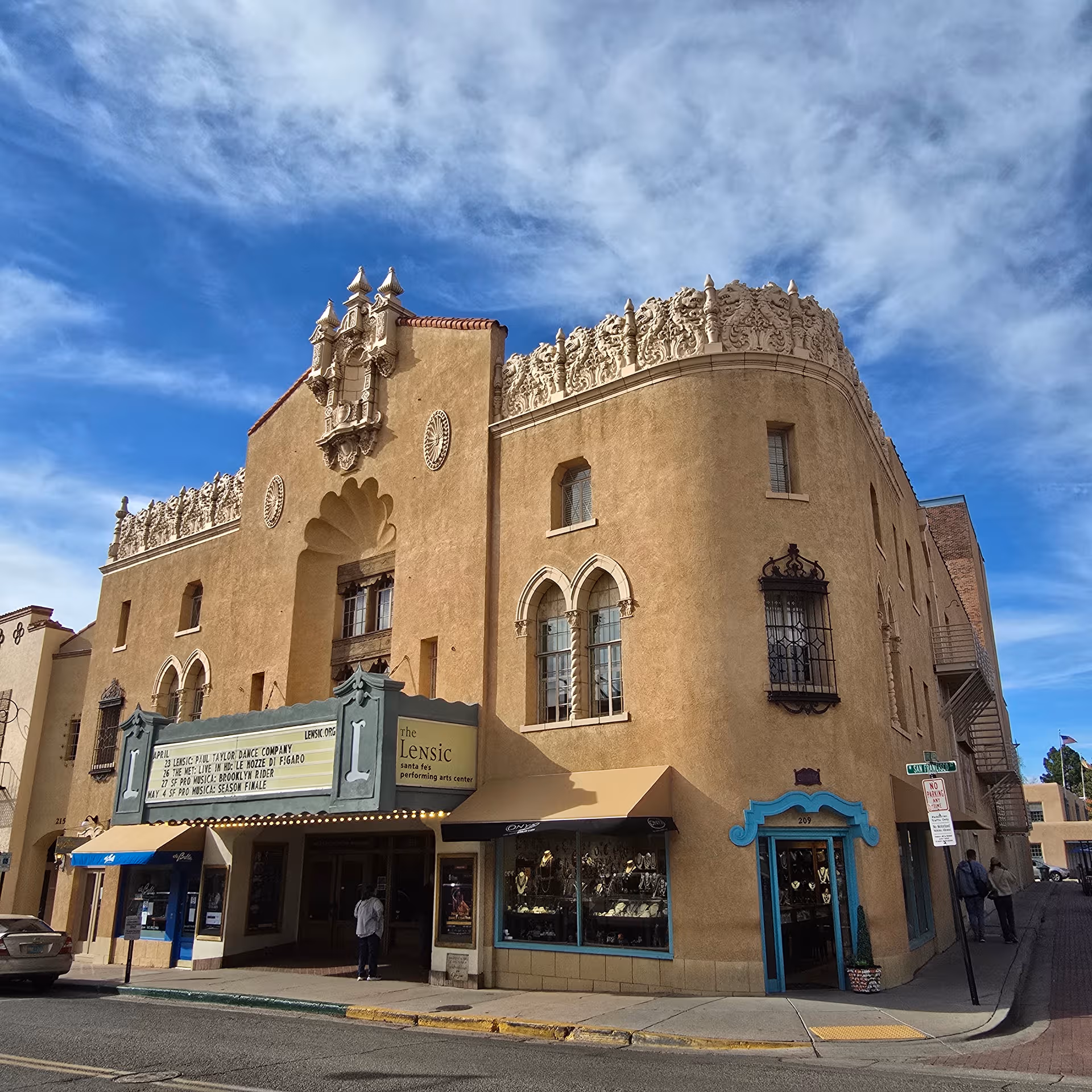 Exterior view of a tan, ornate building with a decorative upper facade and marquee.