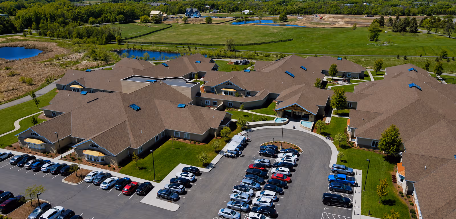 Aerial view of a senior living campus with brown-roofed buildings and a circular driveway.