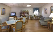 A welcoming lounge with sofas, armchairs, tables, and a bookshelf in a senior facility.