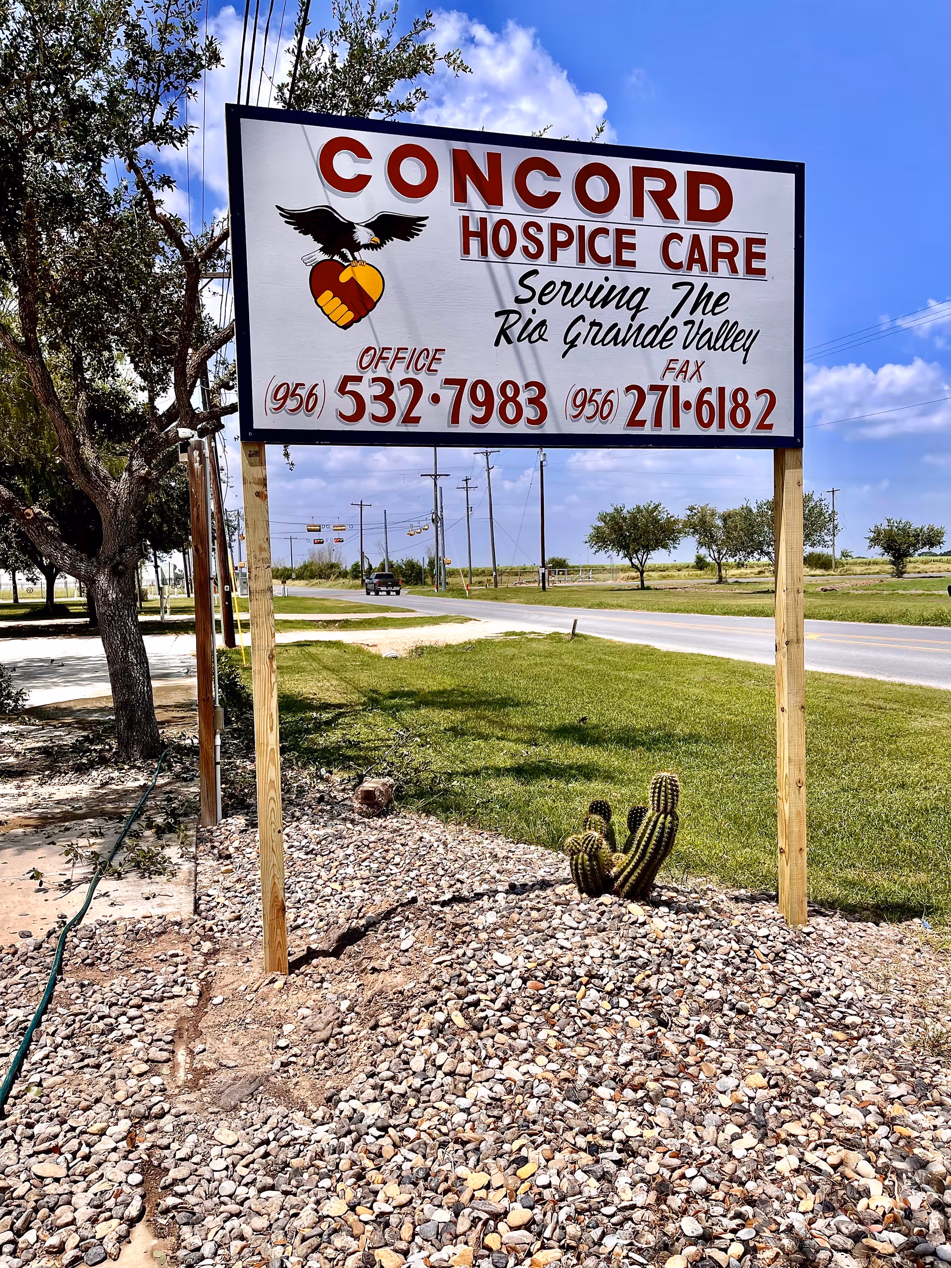Concord Hospice Care sign on wooden posts amid gravel, near road.