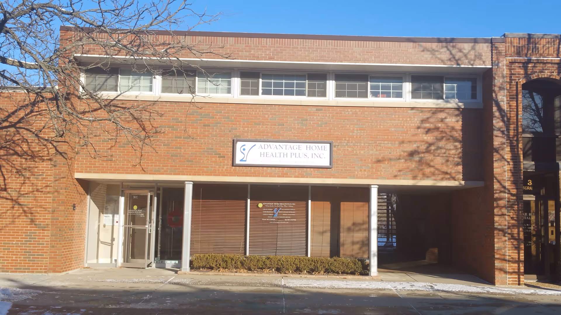Brick storefront of Advantage Home Health Plus, Inc. with glass entrance and office windows.