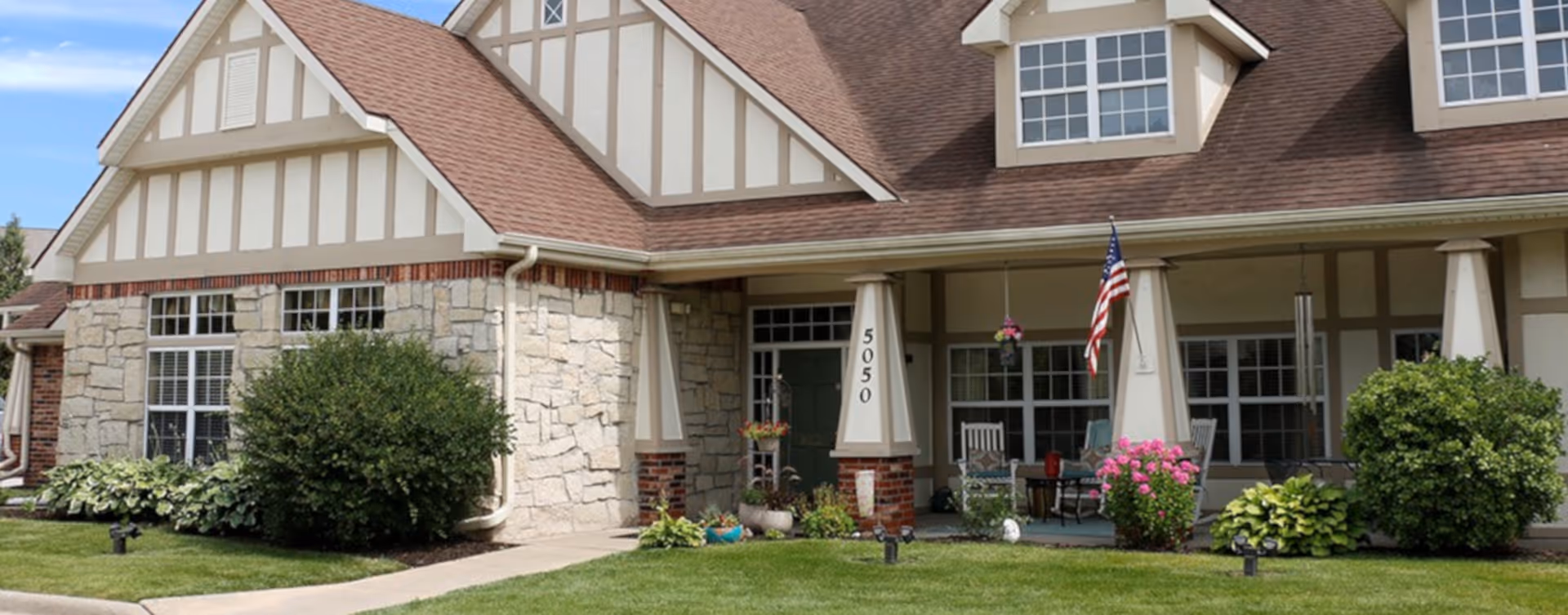 Front view of Bickford of West Des Moines, beige stone senior living building with a porch.