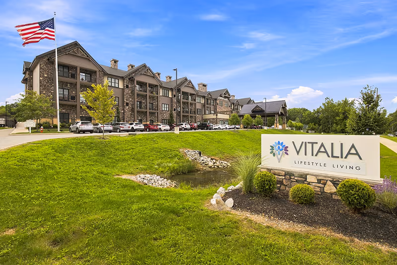 Exterior view of Vitalia Active Adult Community North Royalton with sign, flag, and building.