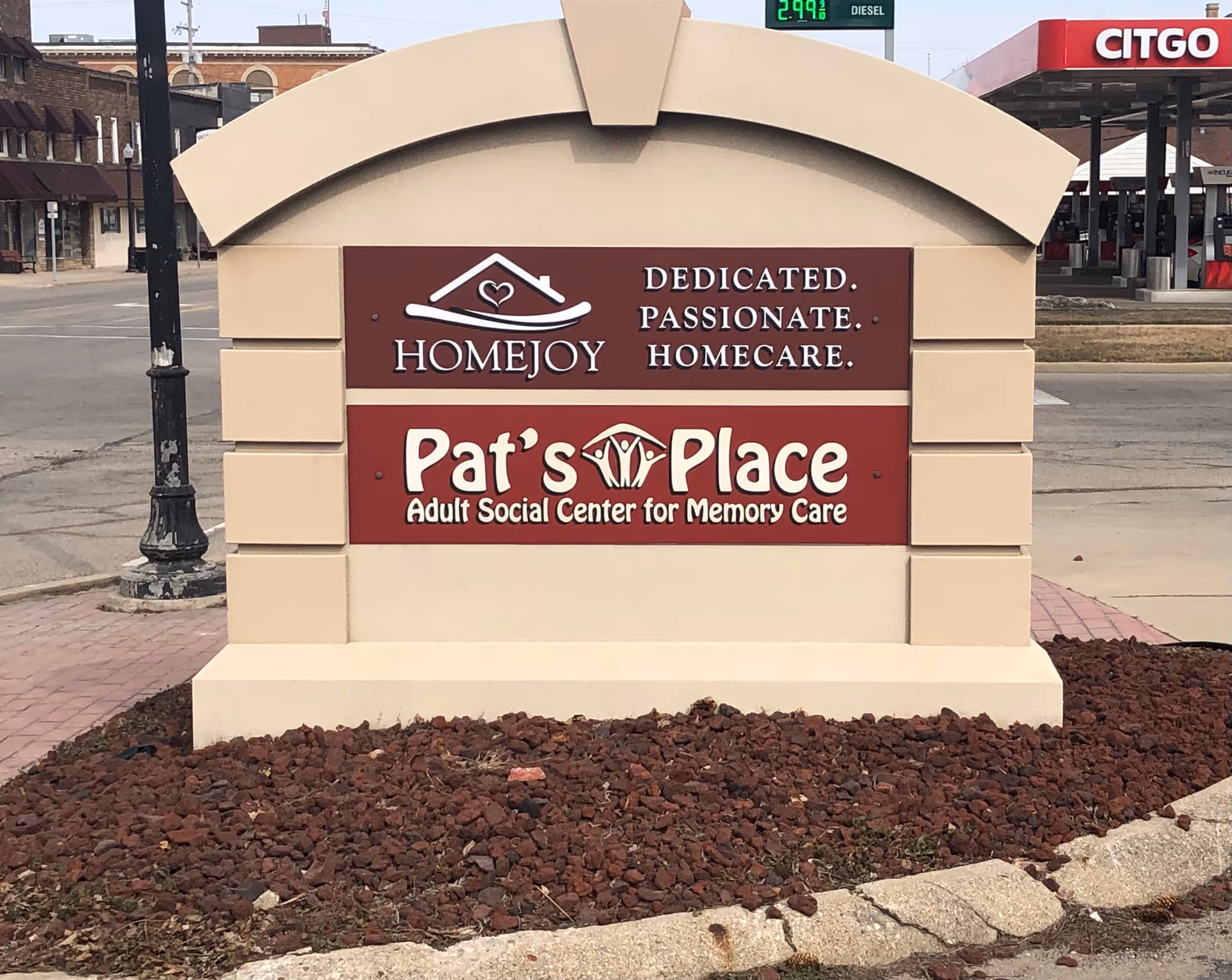 Exterior sign displaying HomeJoy and Pat's Place memory care facility branding in a parking lot.