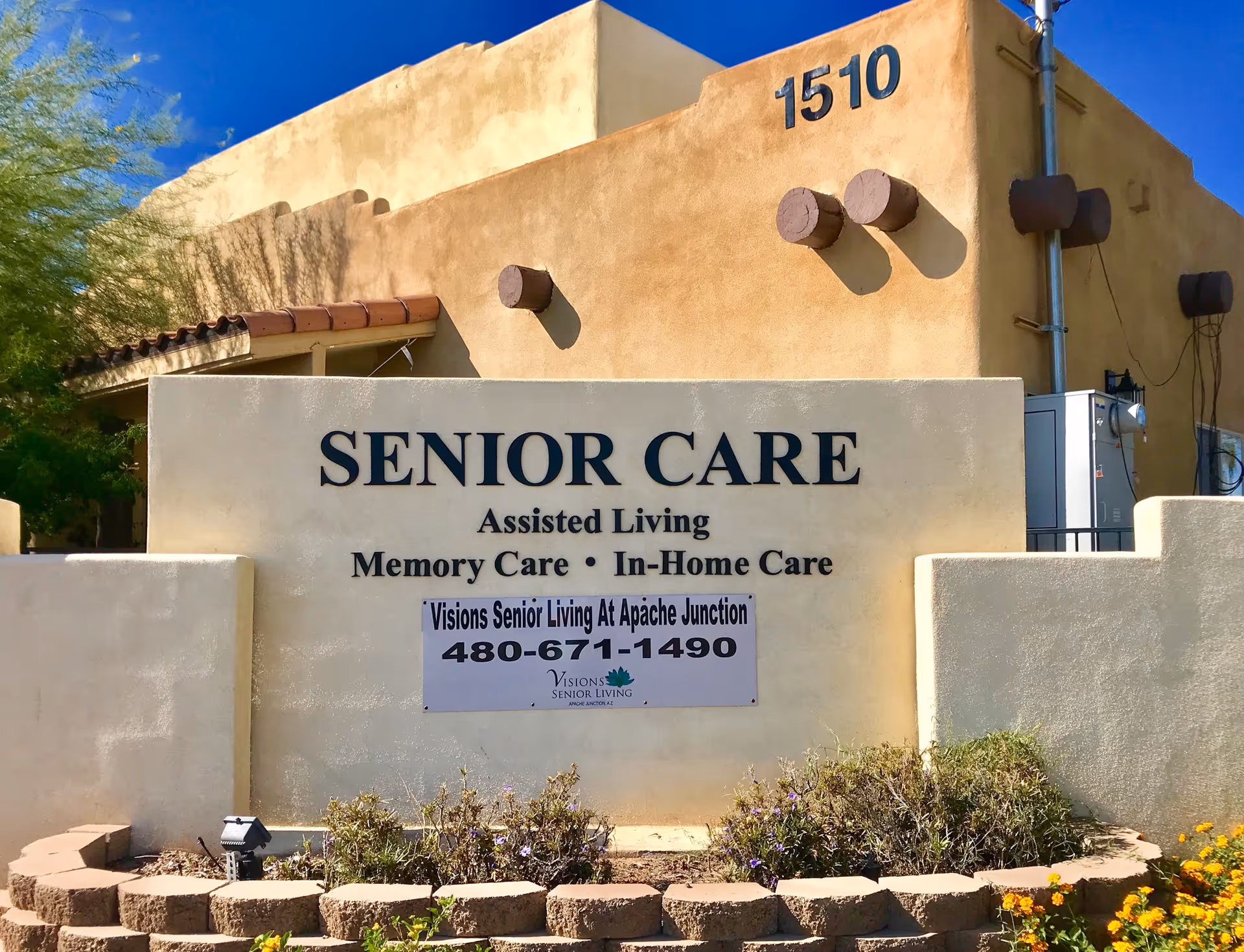 Exterior view of a senior care facility sign and landscaping in Apache Junction.