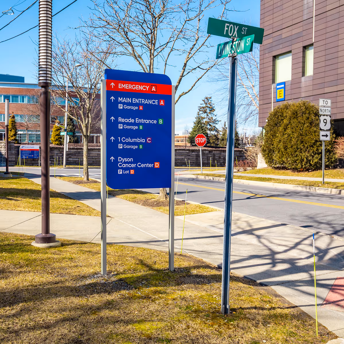 Exterior street scene with a large blue directional sign near a medical building