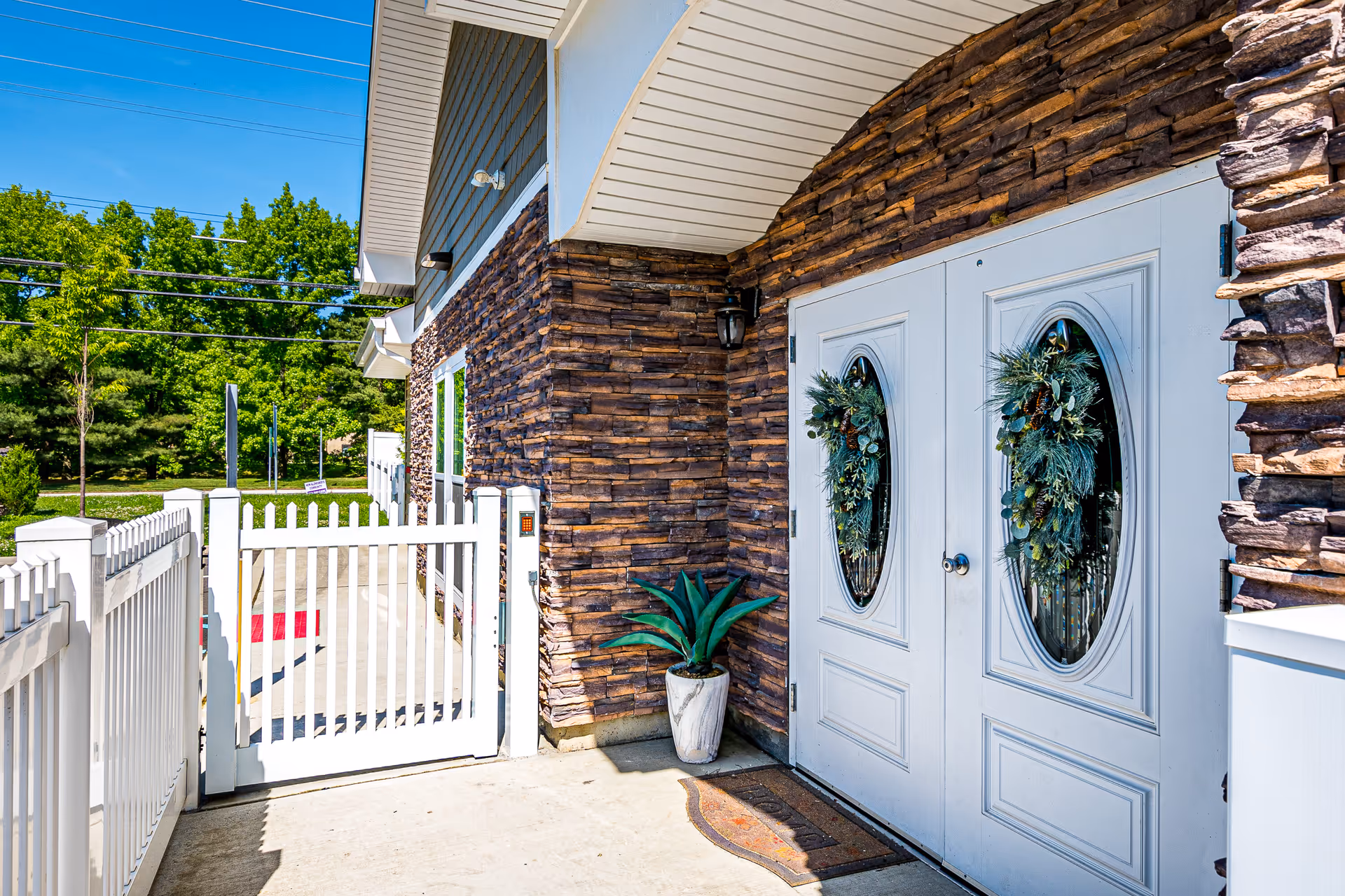 Exterior entrance of Peaceful Pines Residence Memory Care Community with double doors and stone facade.