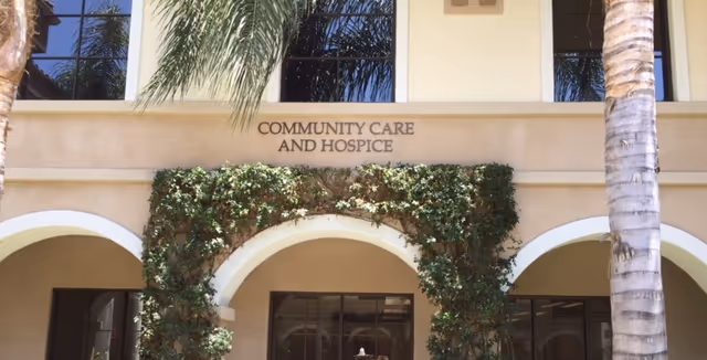Facade of a seniors facility with arched entryways and ivy, sign reads Community Care and Hospice