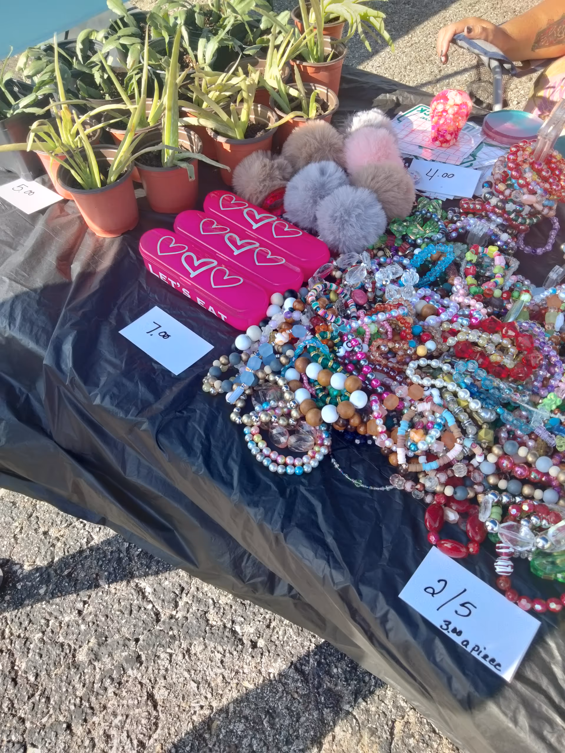 Outdoor market stall with colorful beads and accessories on a table.