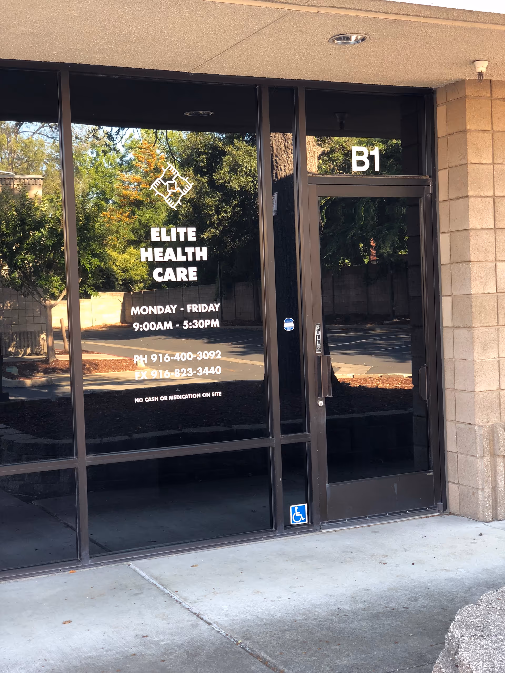 Glass entrance of Elite Health Care shows hours and an accessibility sign.