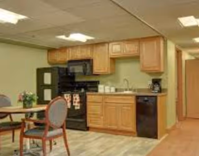 Interior kitchen area with wooden cabinets, stove, and small dining table with chairs.