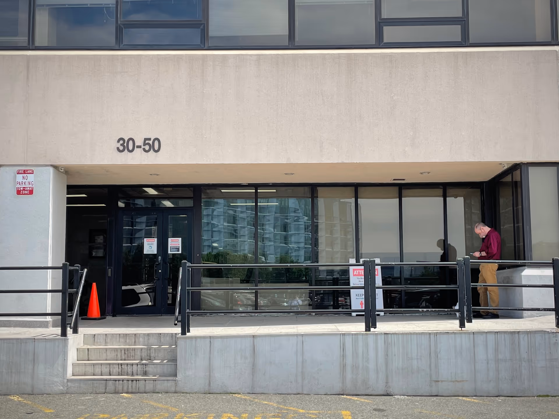 Exterior view of a building entrance with glass doors and a man nearby