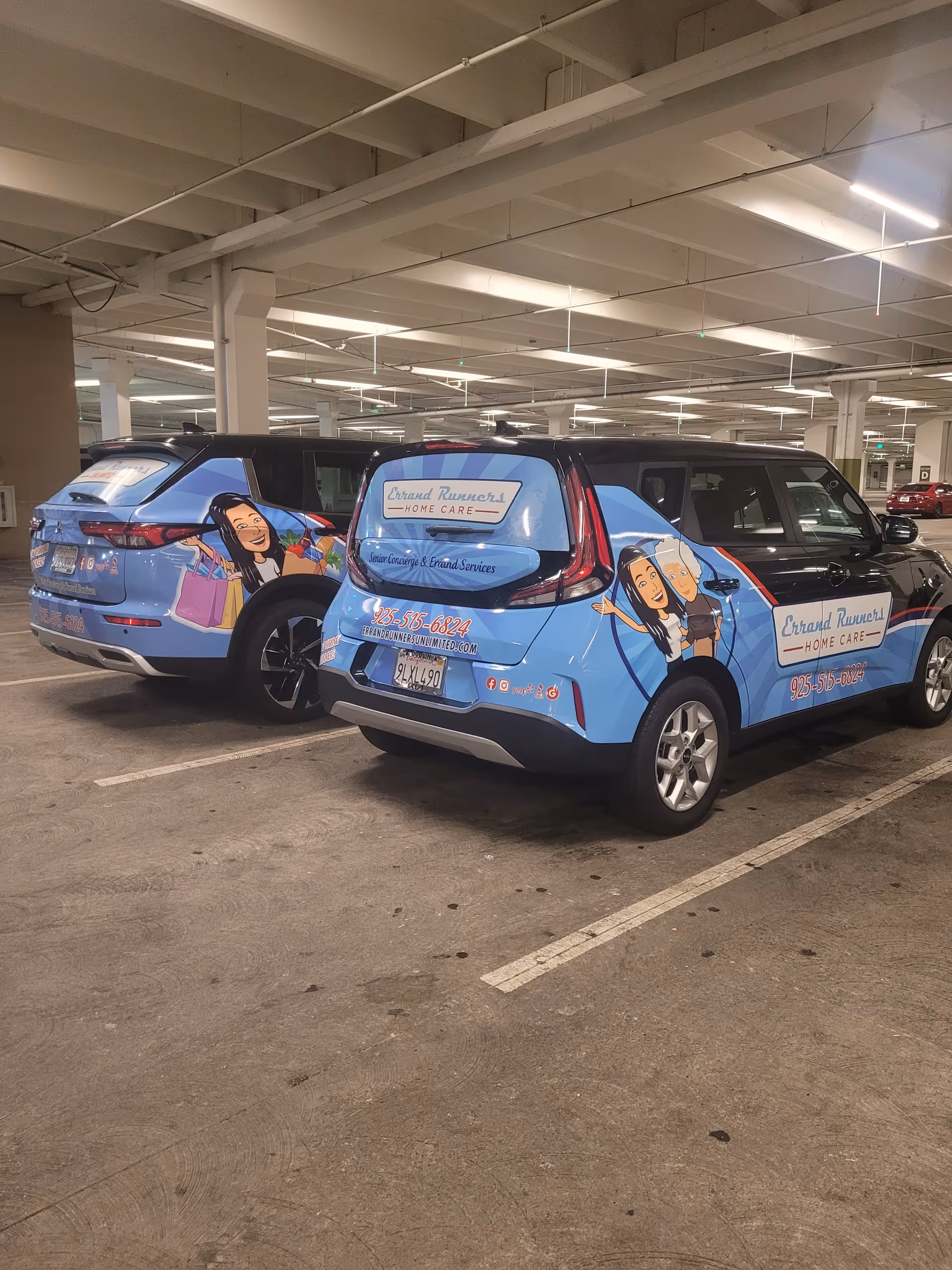Two branded blue Errand Runners Unlimited vans parked inside a dim underground parking garage.