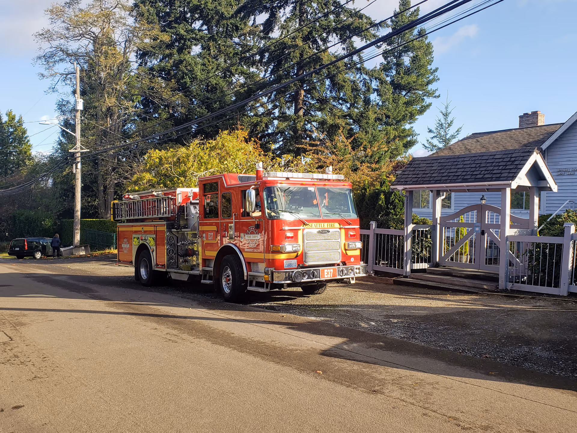 Red fire truck parked on a street in front of a gated senior living facility.