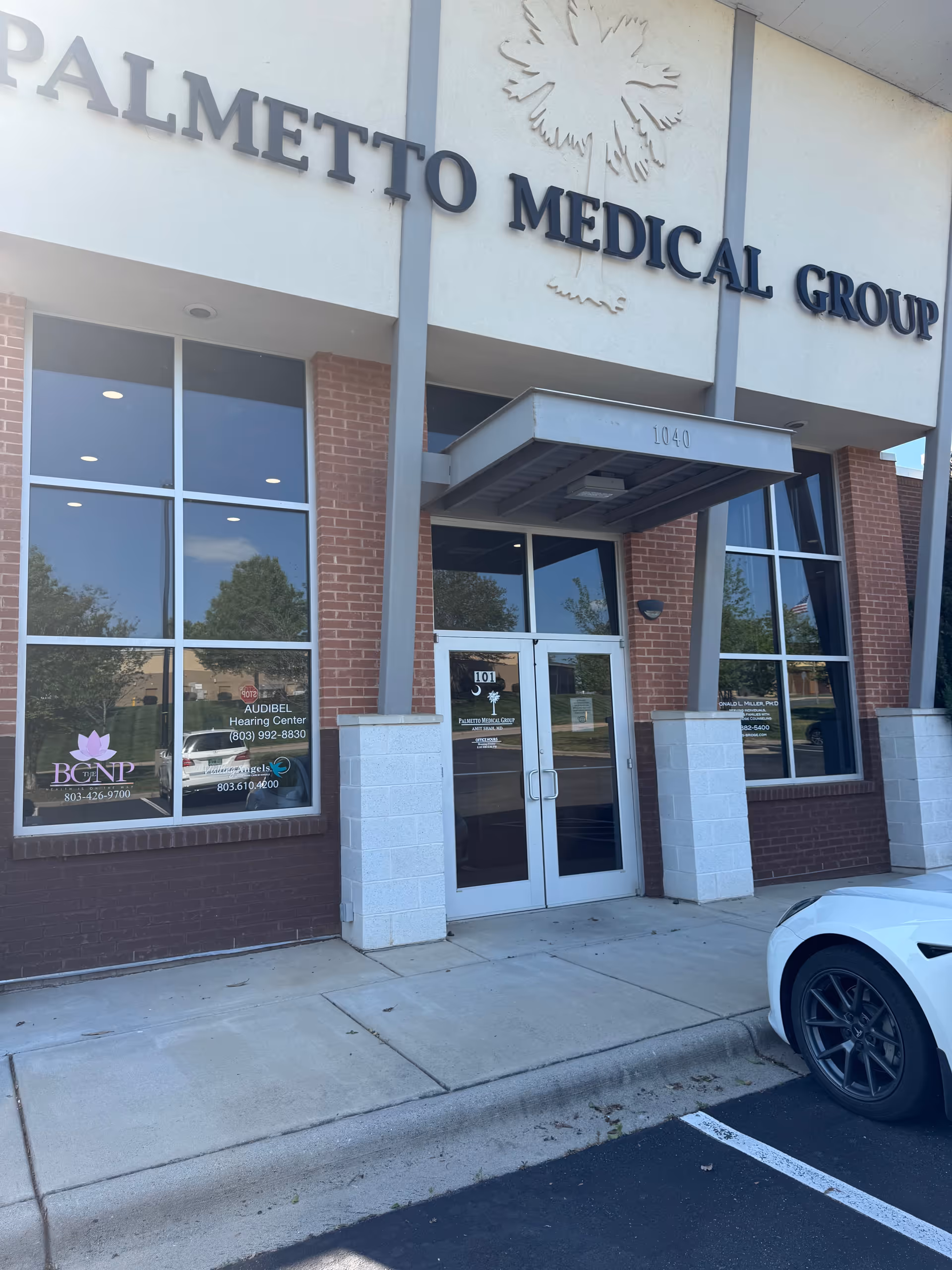Front exterior of Palmetto Medical Group with glass entrance doors and brick facade.