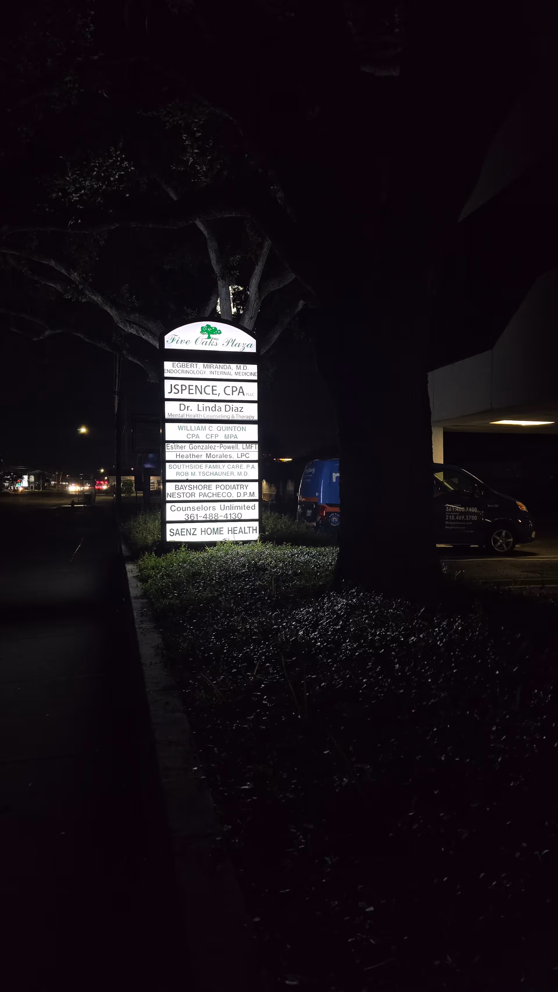 Night exterior of a building with a signboard listing medical offices including Saenz Home Health.