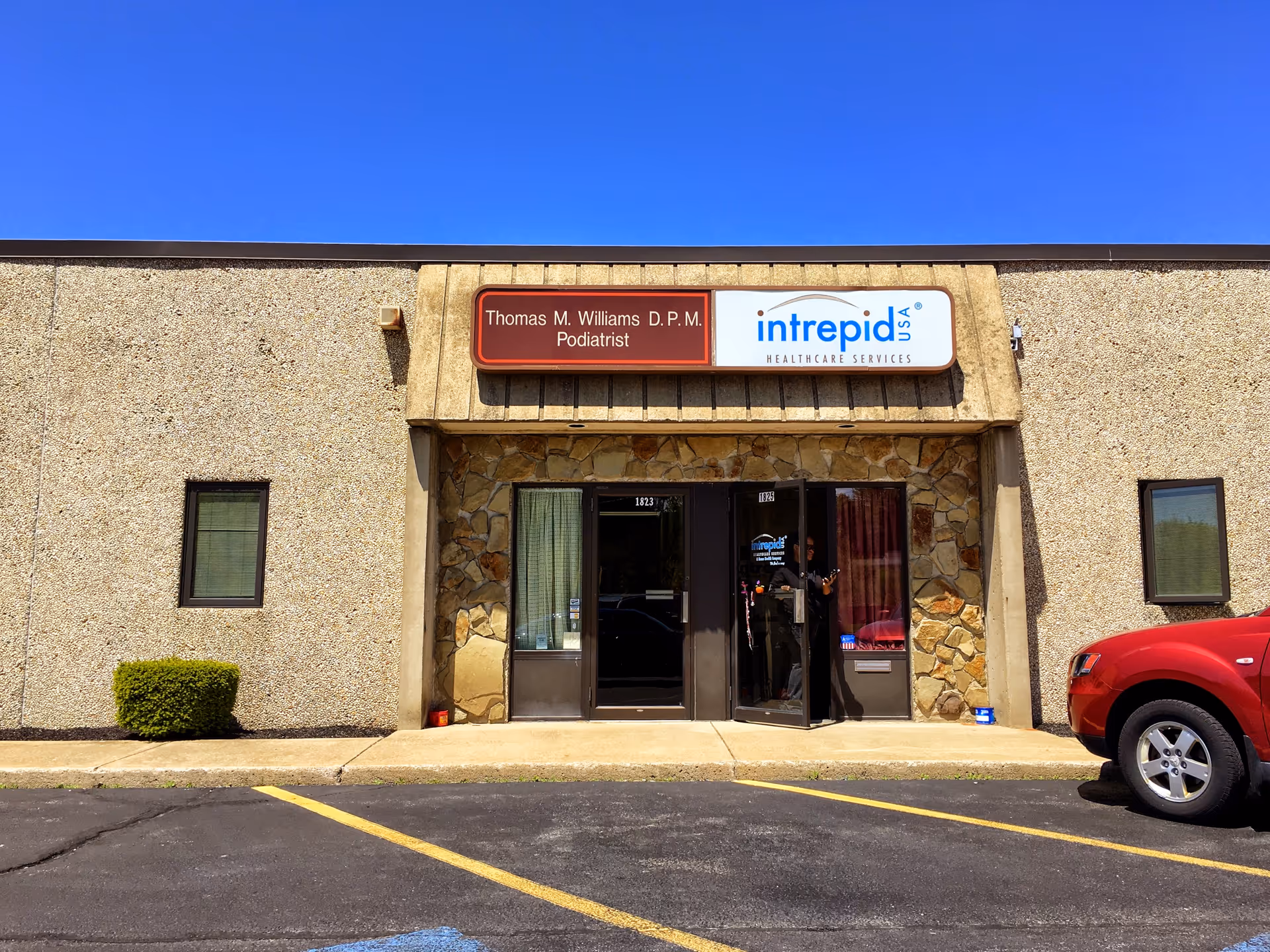 Exterior view of a building entrance with Intrepid USA Healthcare Services signage and a red truck.