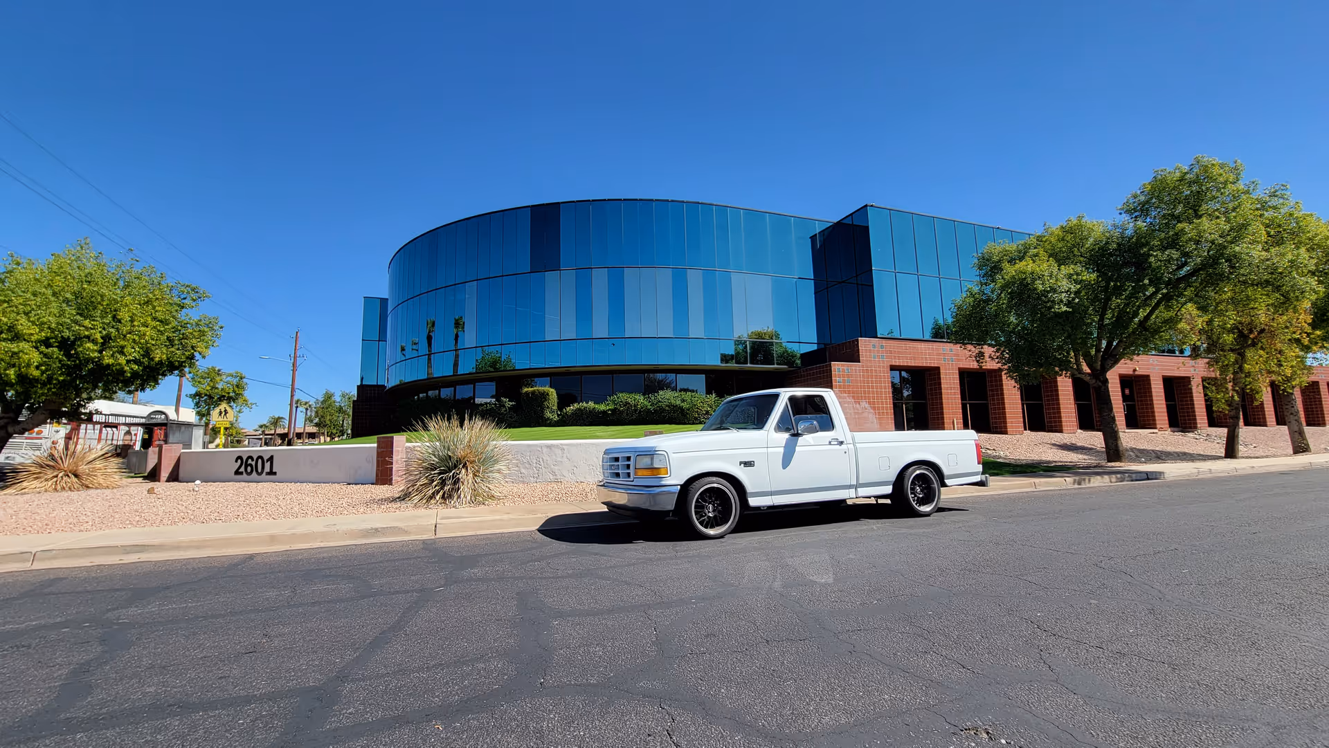 Modern glass-front senior living facility building with a white pickup truck parked outside.