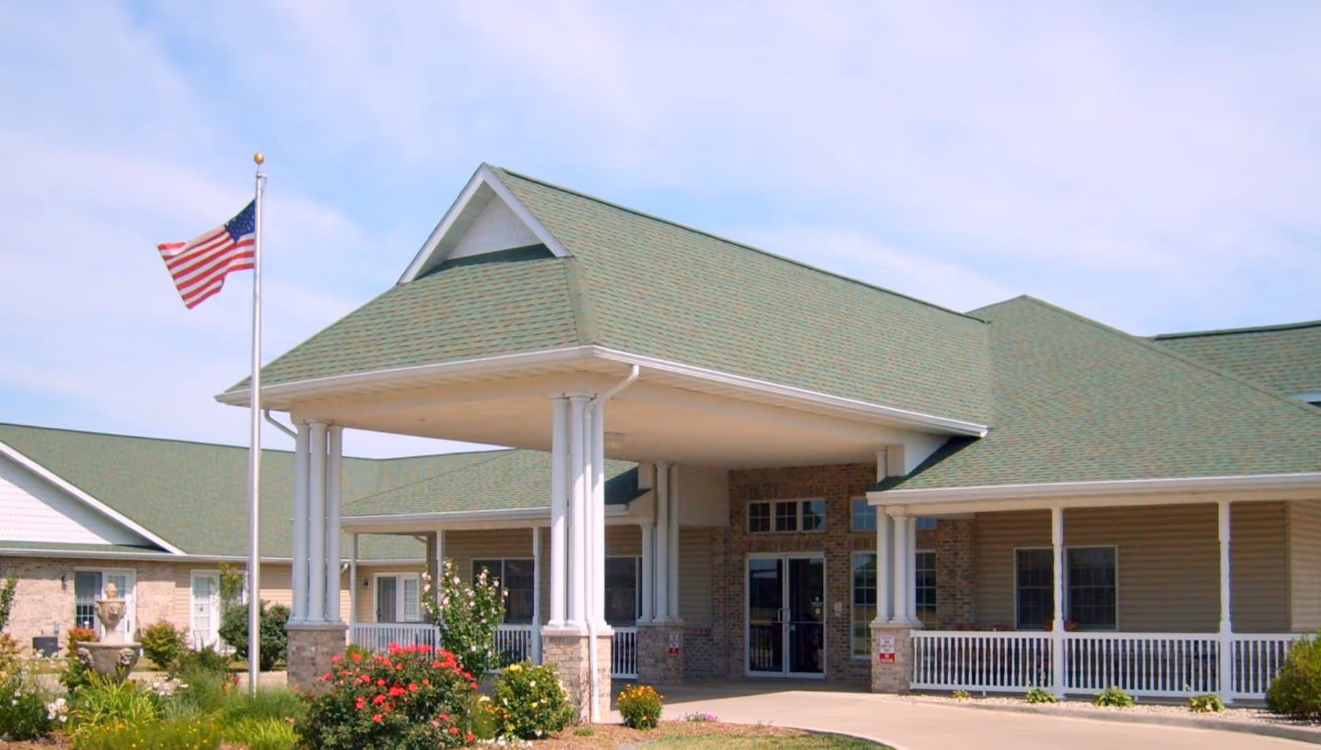 Front entrance of The Glenwood Supportive Living facility with columns and an American flag.