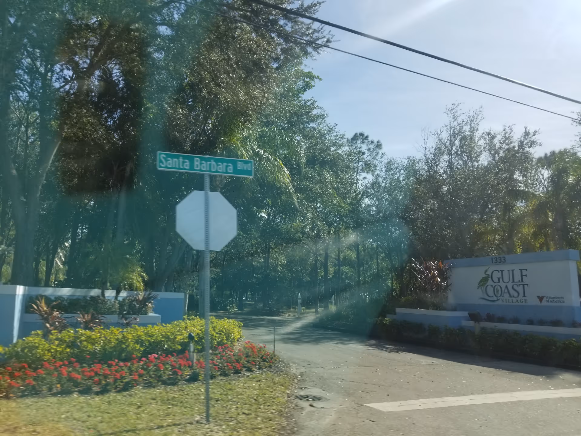 Entrance signage for Gulf Coast Village along a tree-lined street with a Santa Barbara Blvd sign.