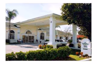 Exterior view of The Windsor of Bradenton entrance with a porte-cochere and parked cars.