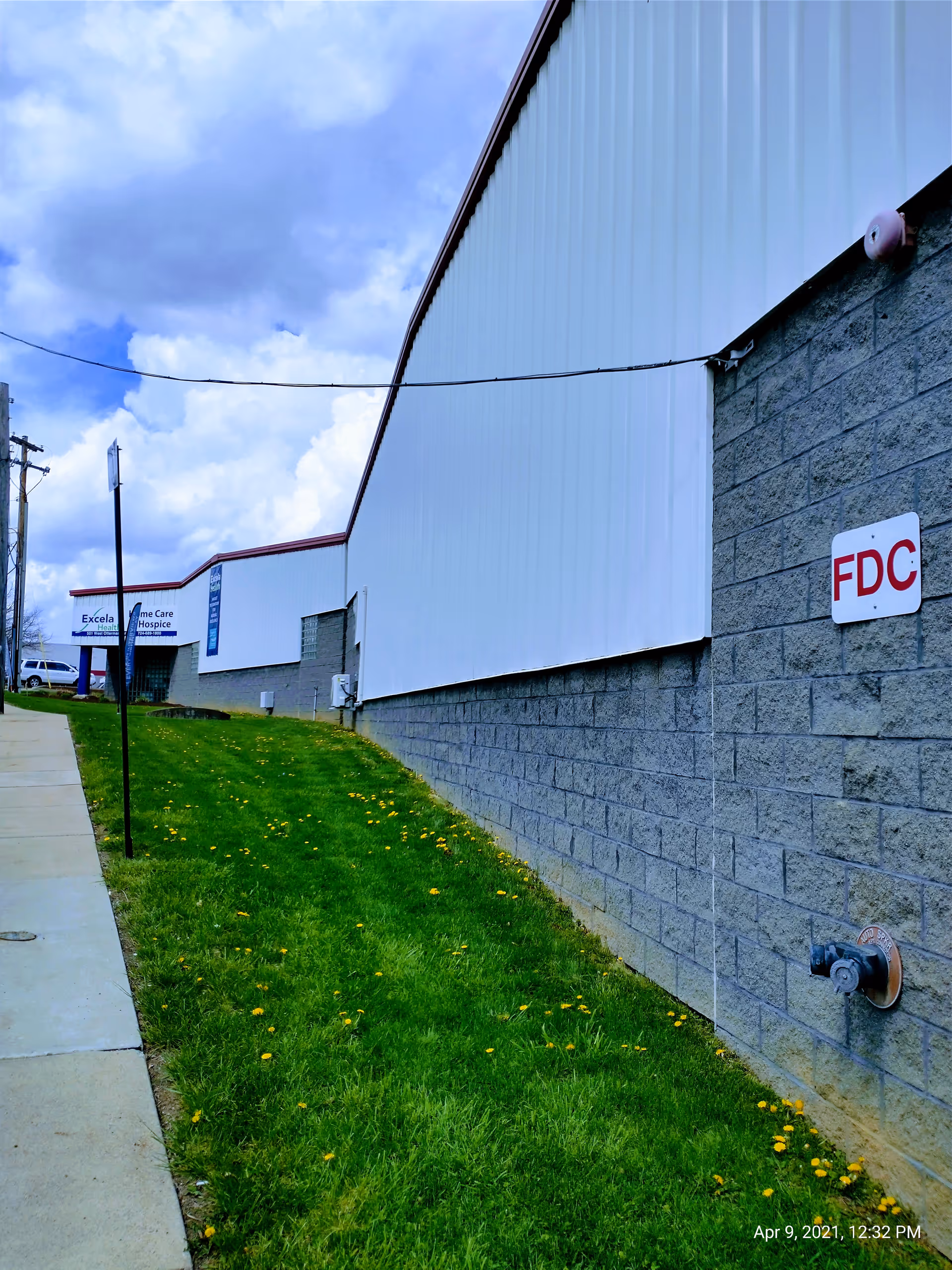 Exterior view of Excela Health Home Care and Hospice building beside sidewalk and grass.