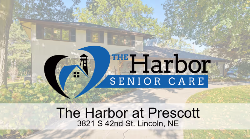 Two-story light-colored building facade with surrounding trees and a translucent Harbor Senior Care logo overlay.