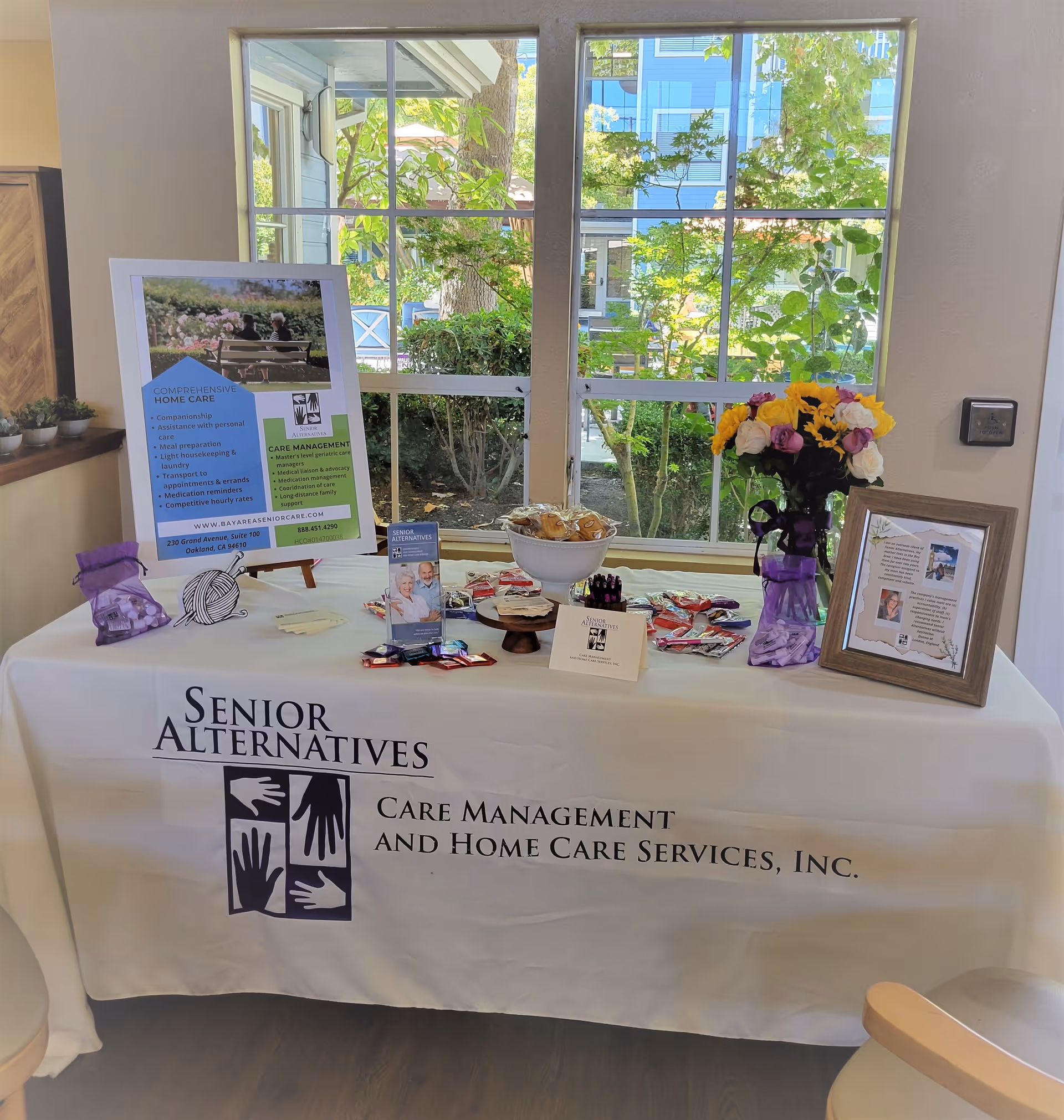 Indoor information table with Senior Alternatives branding, brochures, flowers, and a window view.