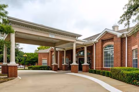 Brick senior living facility entrance with a covered drive-through and columns.