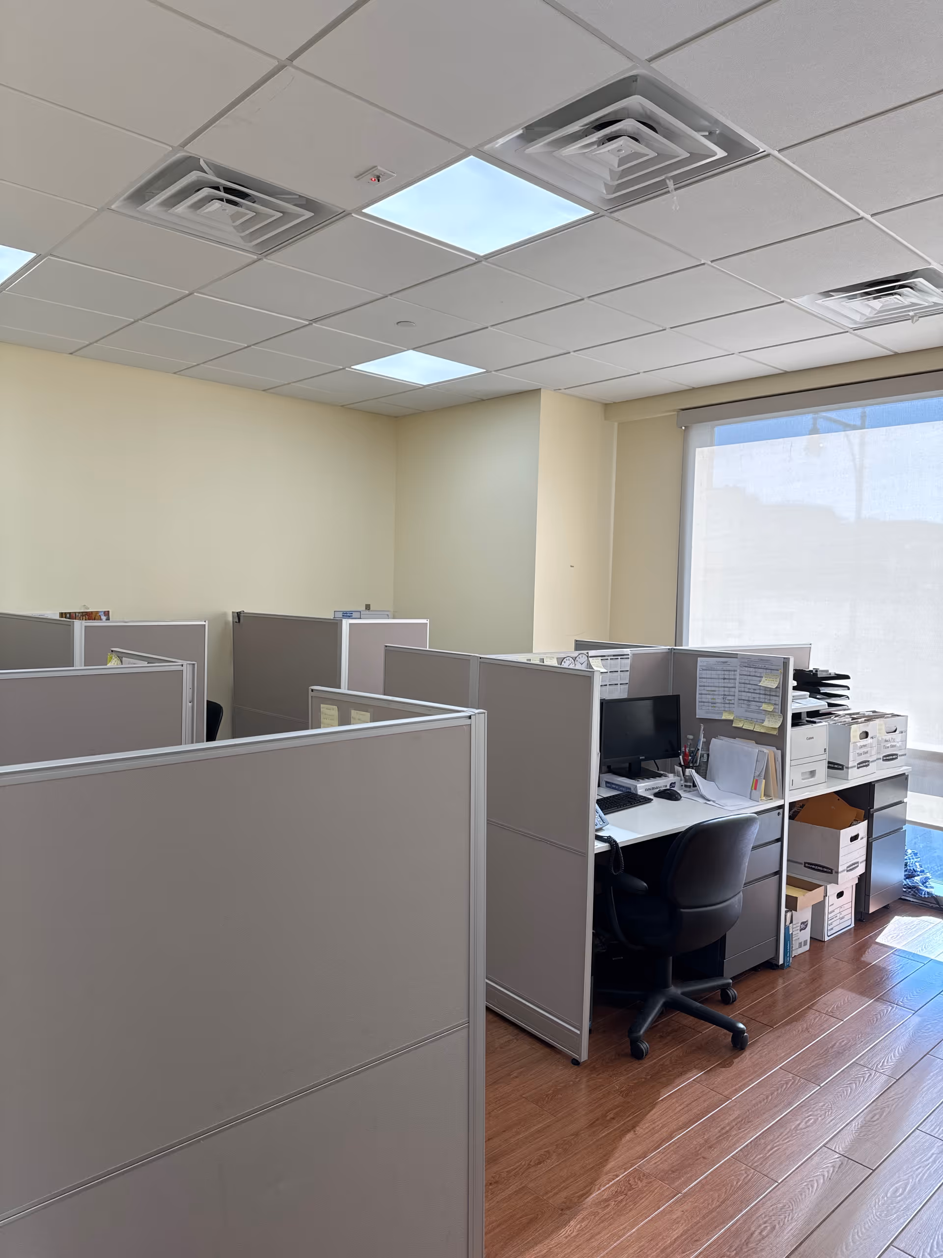 Interior office space with cubicles, desks, and computers in a shared workspace.