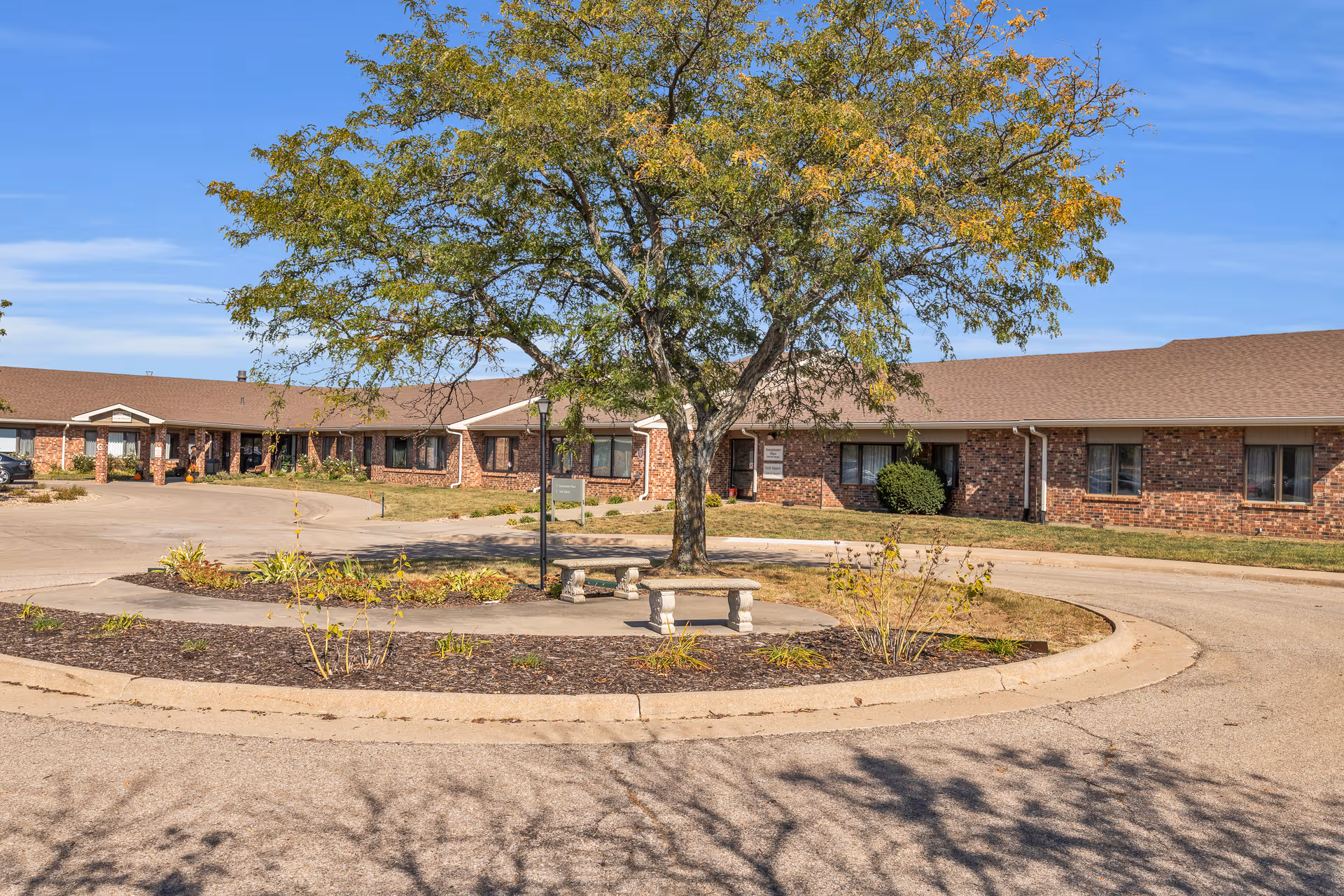 Exterior view of The Gardens at Aldersgate, a brick senior living facility with a circular driveway.
