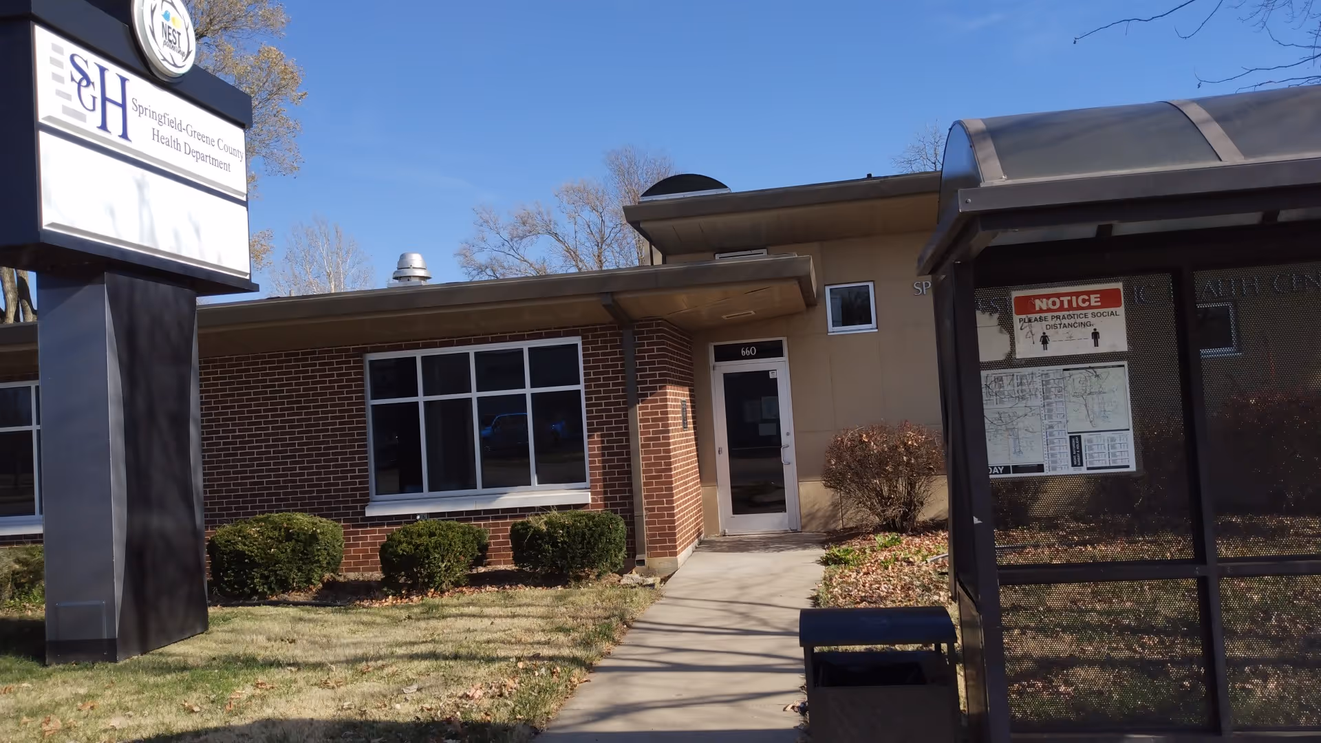 Front view of a brick and beige health center building with walkway and shrubs.