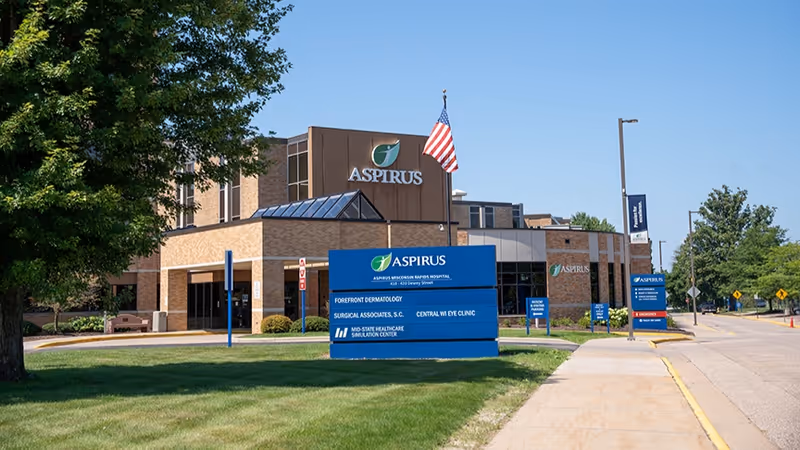 Exterior view of Aspirus facility with blue entrance sign and American flag.