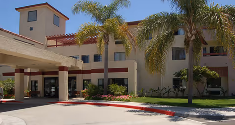 Exterior view of the Brookdale Irvine senior living facility featuring palm trees and a sunny landscape.